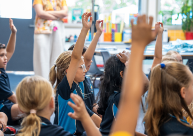 A classroom full of students with raised hands